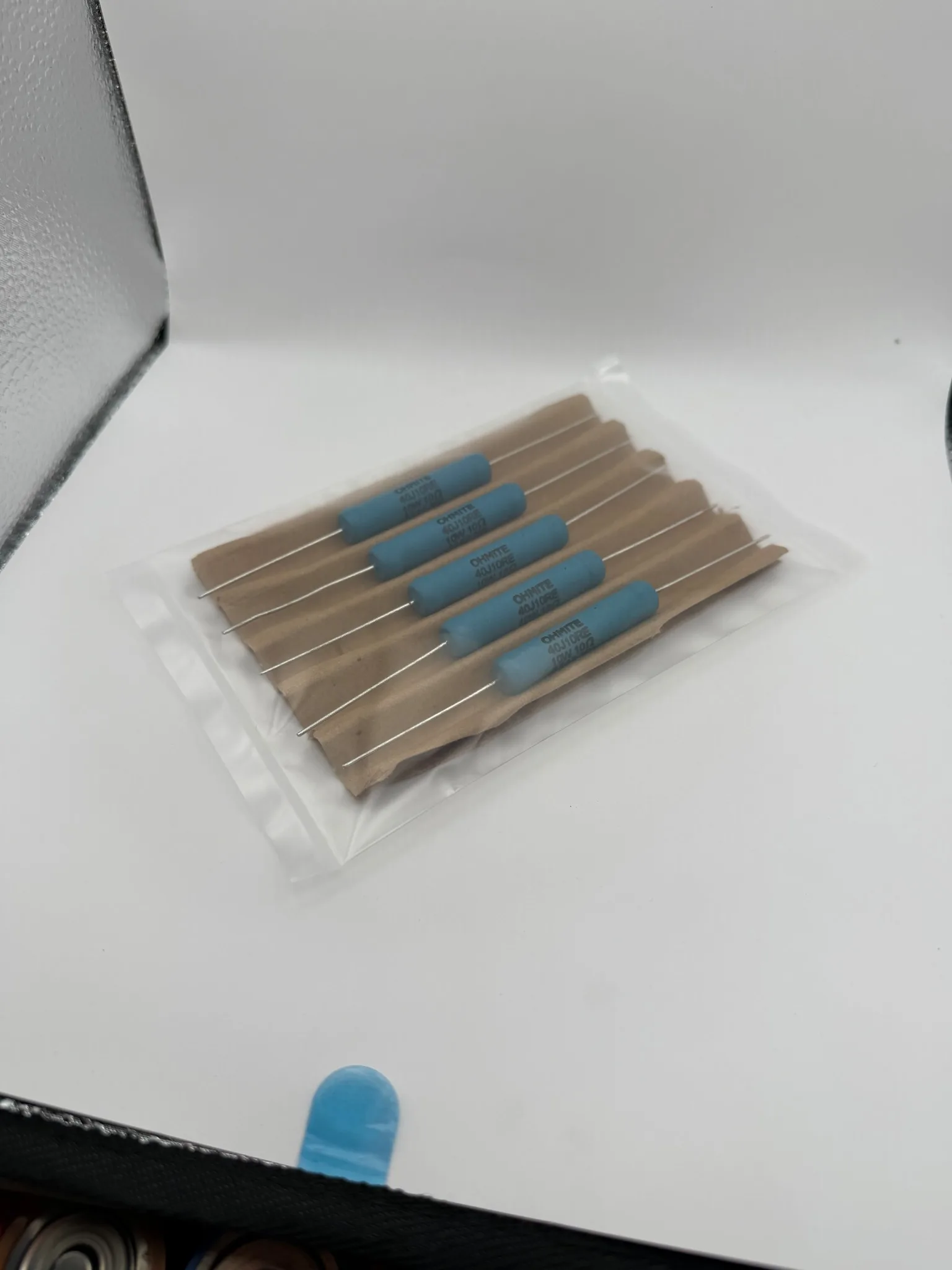 Five blue Ohmite 40J10RE axial wirewound resistors in their cardboard separator